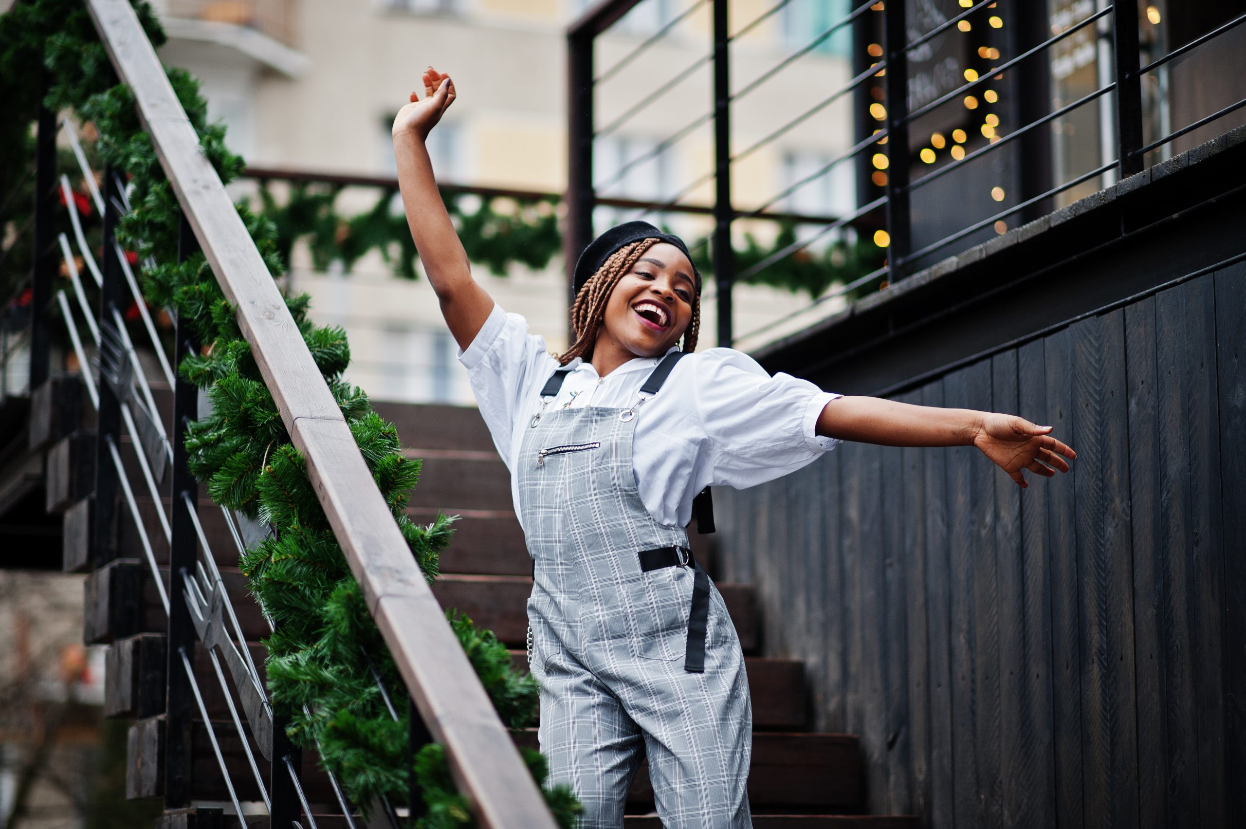 African woman in overalls and beret posed in outdoor terrace happy over paid rent